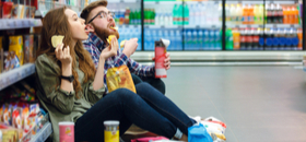 couple eating junk food in a supermarket aisle