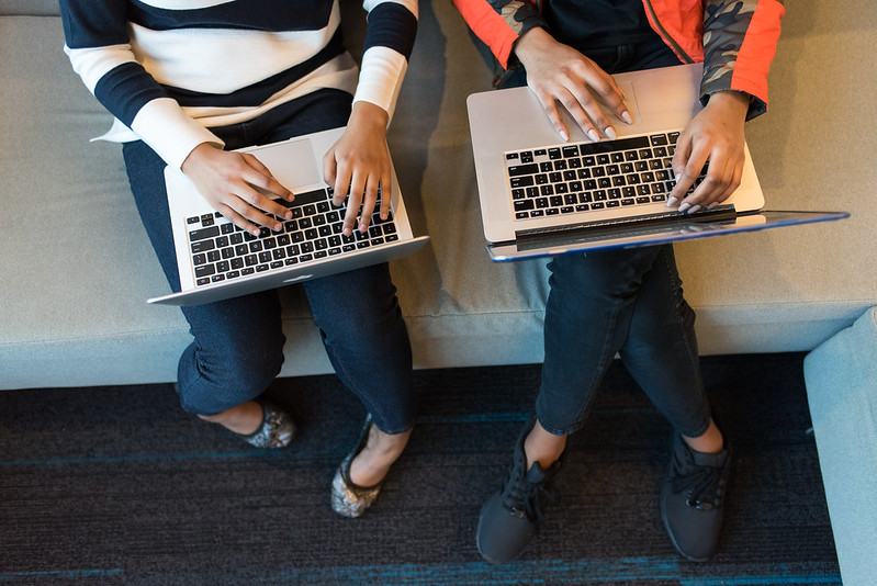 Two women use their laptops.