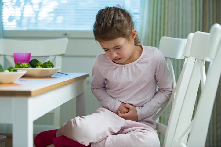 Child sitting at the table in the kitchen with stomach pain
