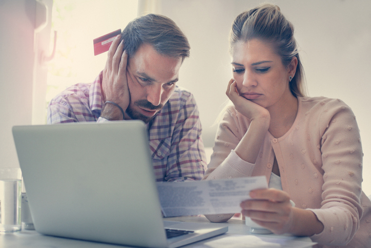 Couple looking at a bill by the computer stressed