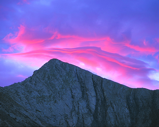 Blue mountaintop against pink sunset clouds by John Fielder