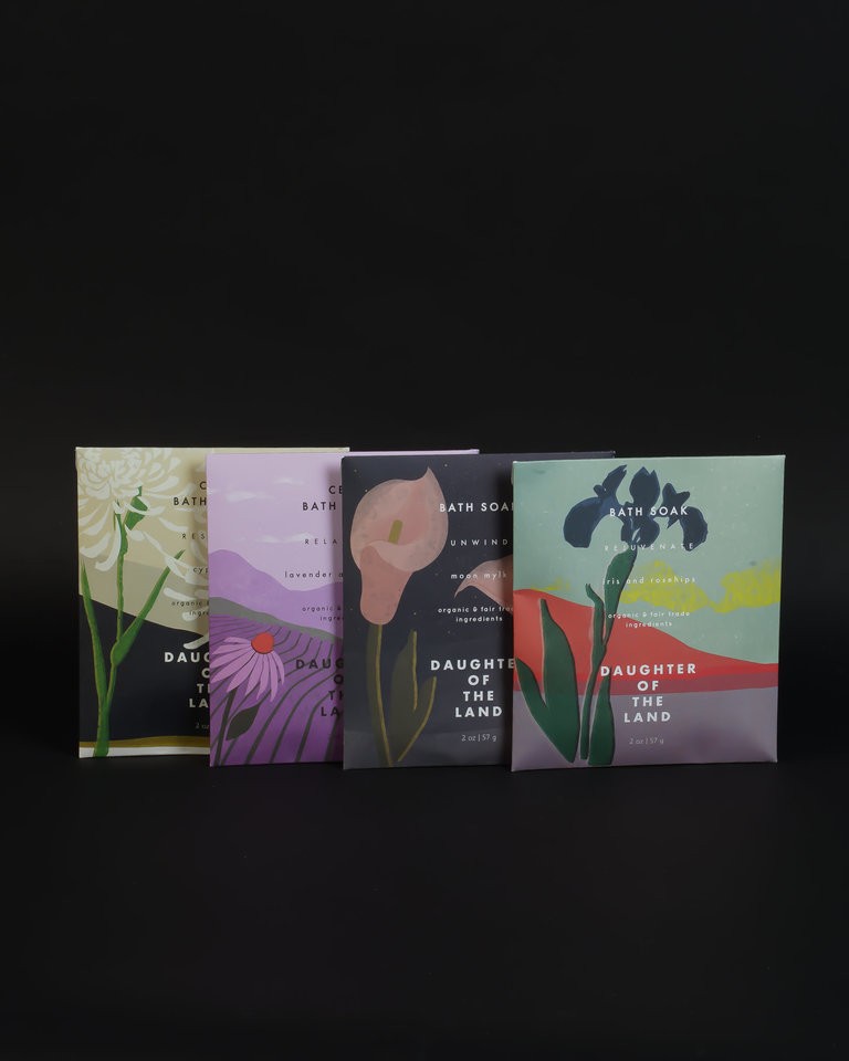 Four individual single soak bath salts line up in a row featuring gorgeous floral imagery.