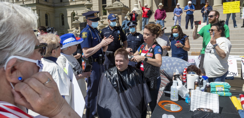Protester getting a haircut at a state capitol, no mask