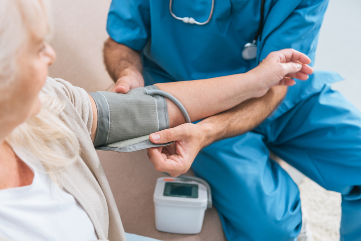 Caregiver measuring blood pressure to senior woman 