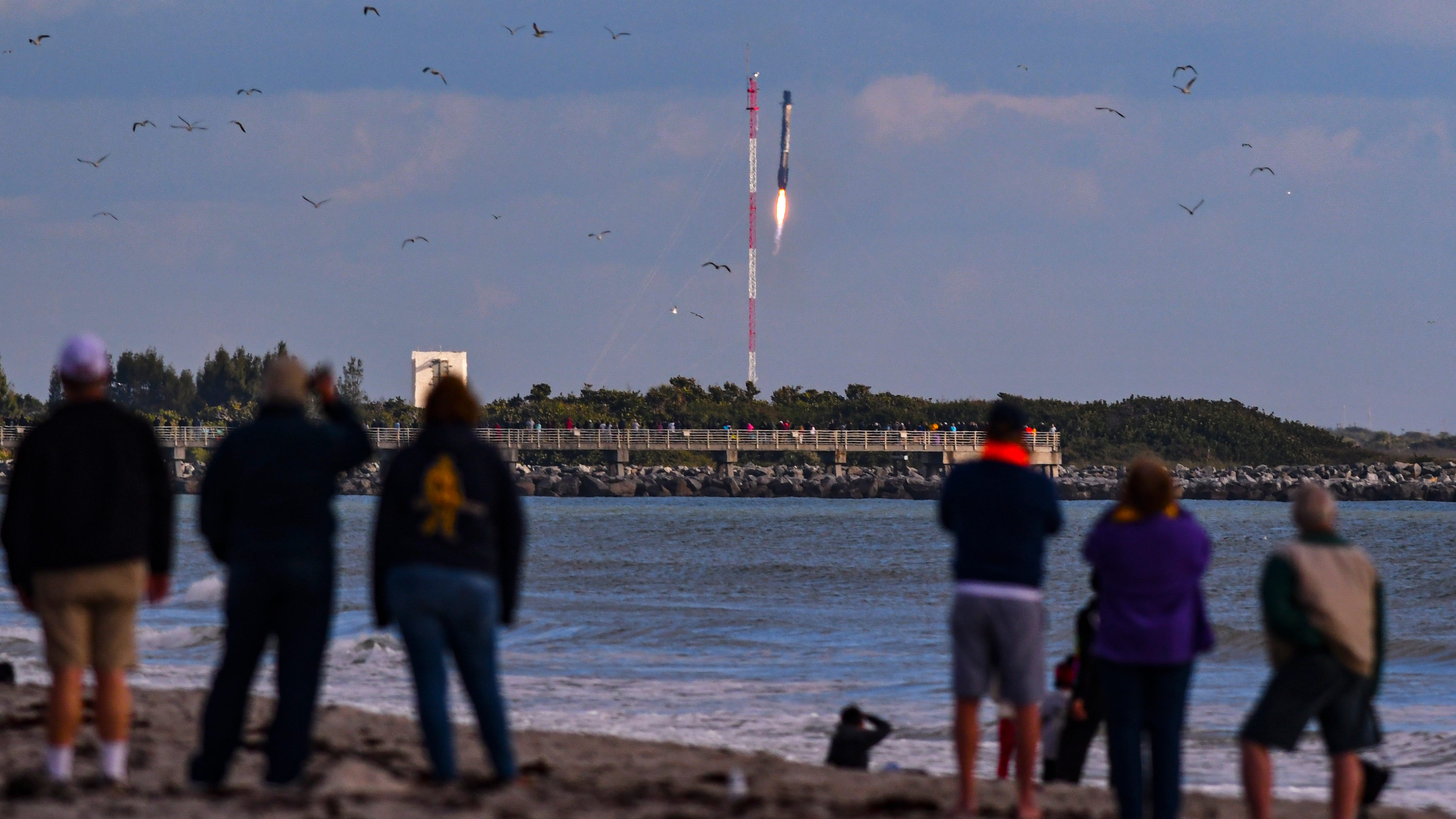 People on the beach in Cape Canaveral watch the booster landing at Cape Canaveral Space Force Station. SpaceX launched a Falcon 9 rocket from Pad 39A at Kennedy Space Center on Saturday, Dec. 19, 2020, on a mission for the National Reconnaissance Office.