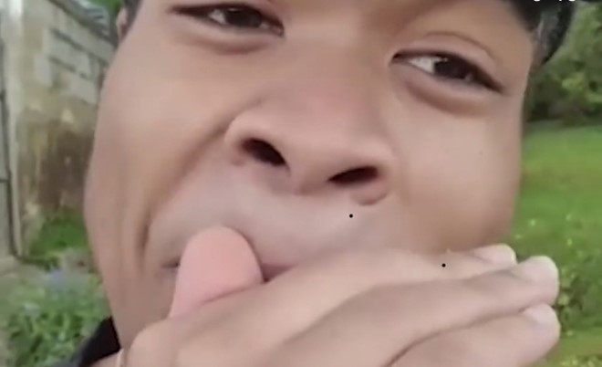 Close up of a boy''s face. He is holding his hand to his mouth, beatboxing.