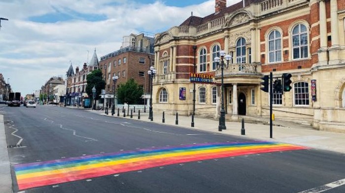 A rainbow road crossing leads to a large Victorian building. A sign ''Battersea Arts Centre'' is visible.