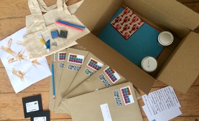 A cardboard box with art supplies unpacked, around it.