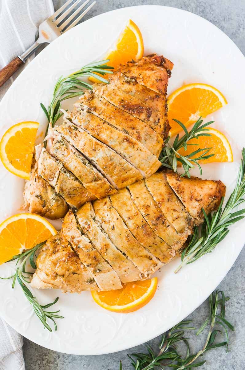roast turkey breast on a platter with rosemary and oranges