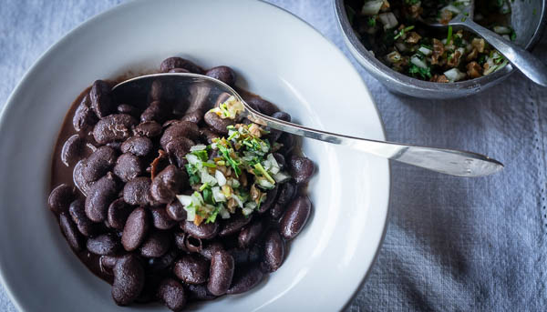A big bowl of dark Ayocote Morado beans, topped with a dollop of Xoconostle relish