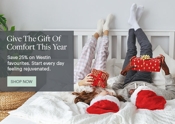 Give The Gift Of Comfort This Year - Save 25% on Westin favourites. Start every day feeling rejuvenated. Shop Now - Lifestyle Couple Laying In Bed With Gifts