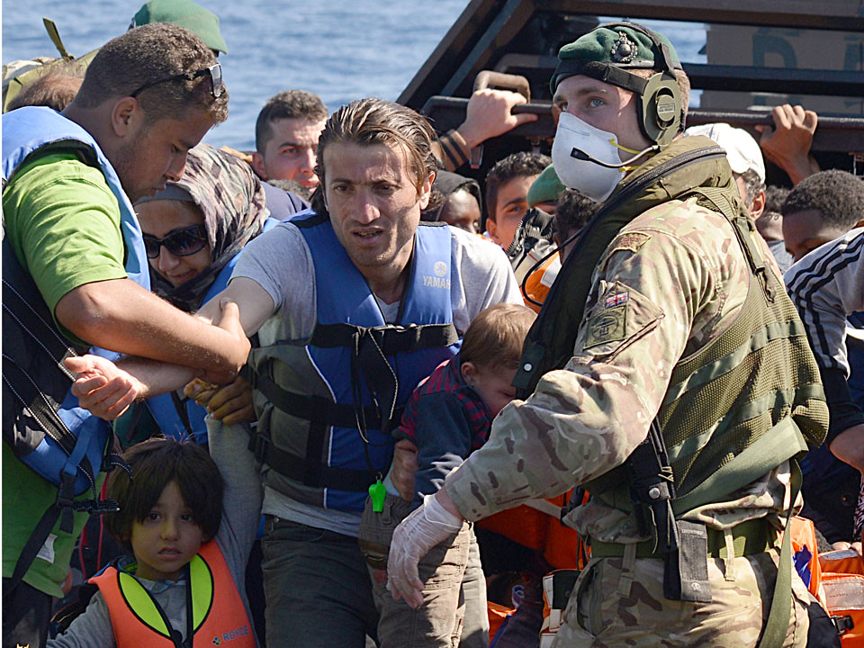 Sailors and marines on the HMS Bulwark help migrants ashore in Italy.