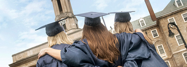 three graduates embracing in front of Old Main