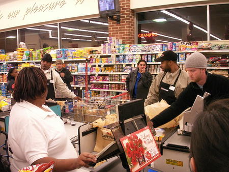 Grocery workers check out customers.
