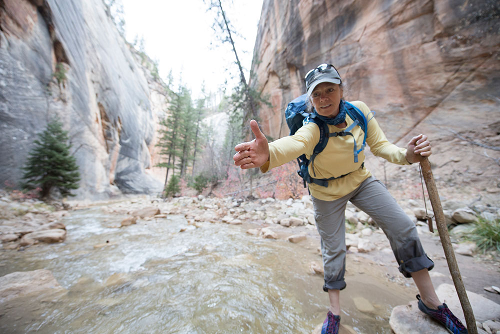 A woman in a canyon holds out her hand to the camera