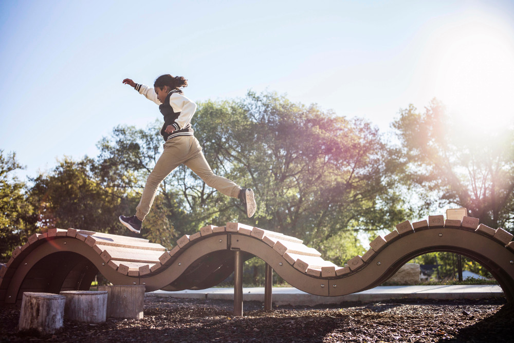 A boy runs across a playground feature
