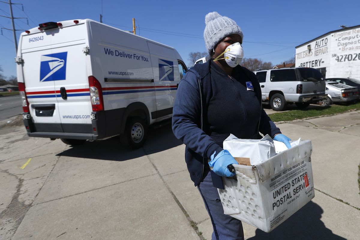 A United States Postal worker makes a delivery with gloves and a mask in Warren, Mich., Thursday, April 2, 2020. (Photo by Paul Sancya for AP Photo)