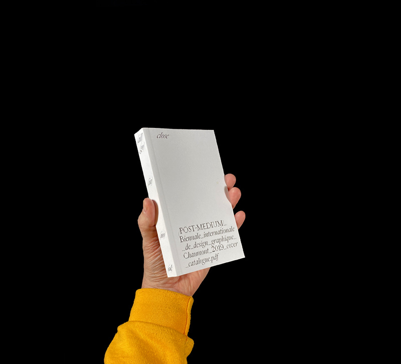 Hand holding holding white book with black text on cover