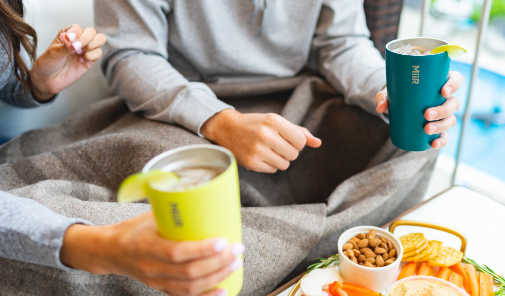 People holding Tumblers at table.