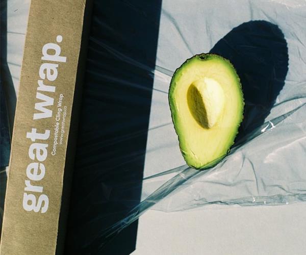 half an avocado sits on cling wrap.