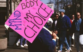 Protest. A protester carries a hot pink sign that reads My Mind, My Body, My Choice.