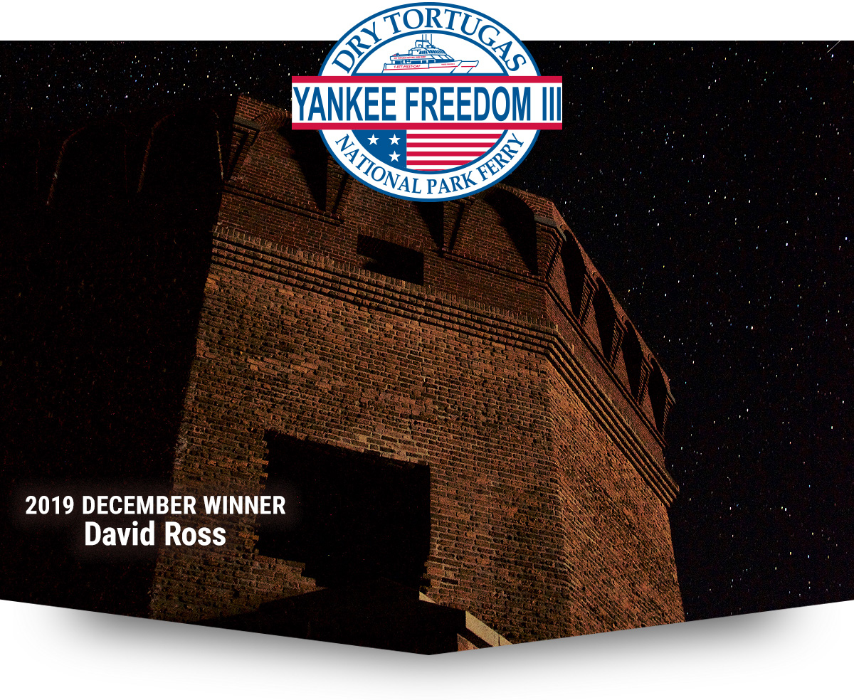 Image of exterior of Fort Jefferson at night showing part of the fort and a sky full of stars, the words '2019 DECEMBER WINNER DAVID ROSS' on the bottom left corner and at the top over the picture, an oval shaped logo that reads Dry Tortugas National Park Ferry Yankee Freedom III'