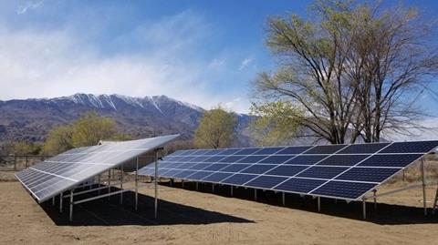 A photo of two rows of solar panels, with mountains in the background