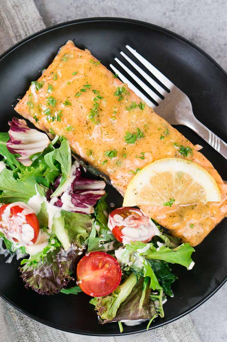 maple mustard salmon on a black plate with green salad