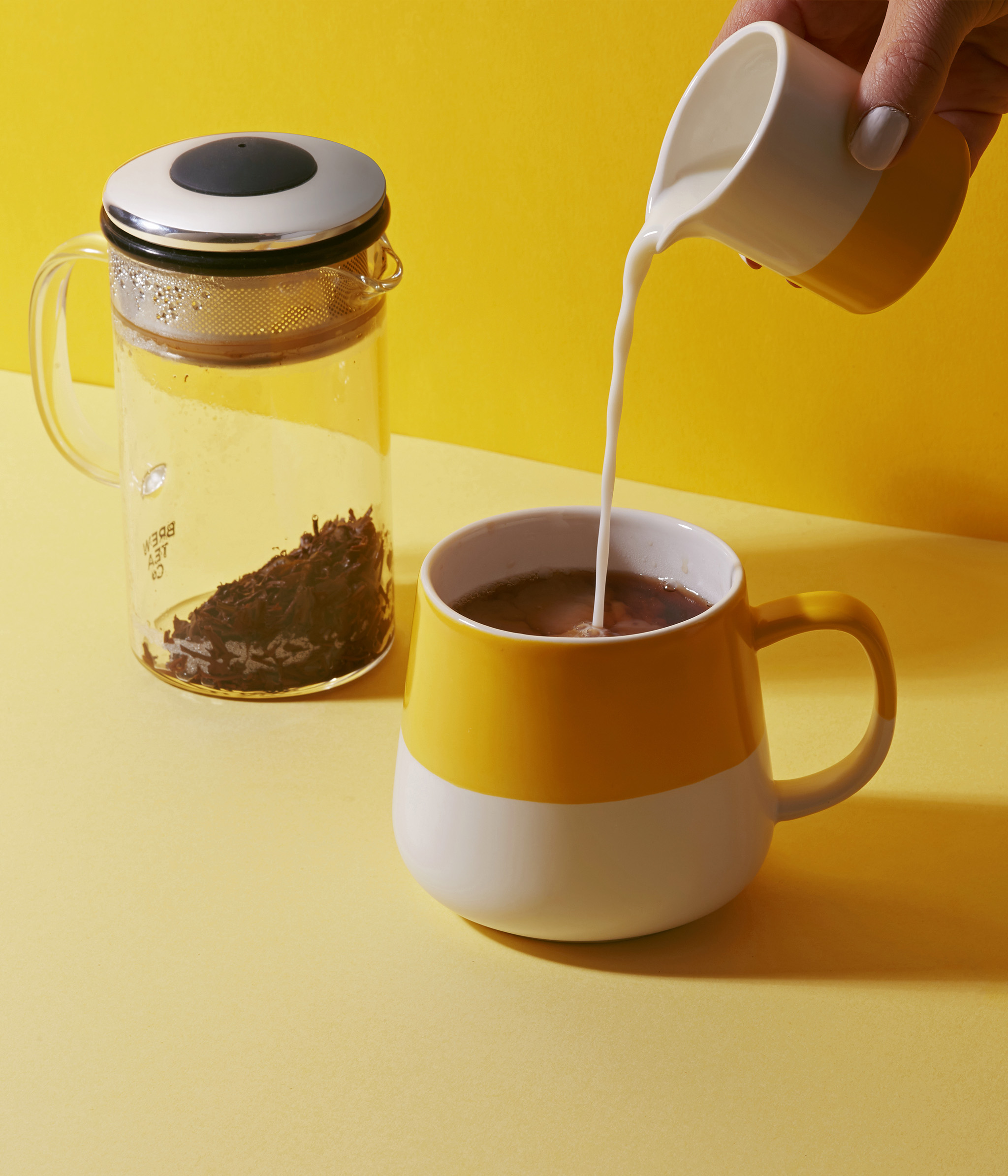Handing pouring milk into a Brew Tea mug
