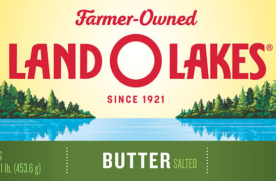 Land-O-Lakes. Packaging for butter that has yellow background with green trees alongside a blue lake.