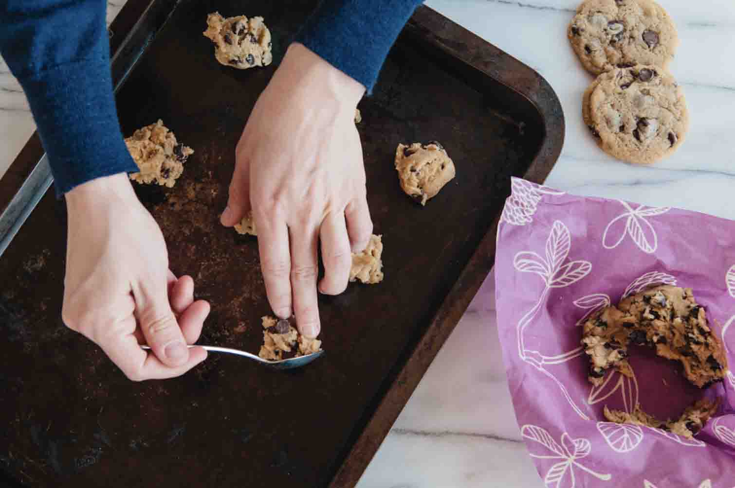 Woman making chocolate chip cookies with dough wrapped in Bee''s Wrap reusable food wrap