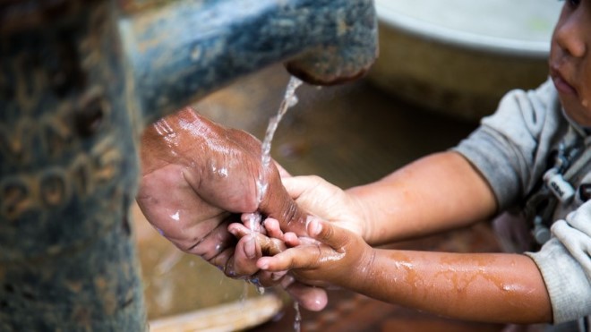 A child washes their hand at a pump station