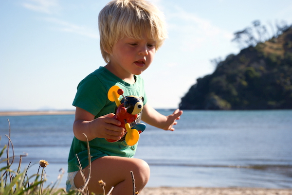 Toddler playing on beach holding buzzy bee toy