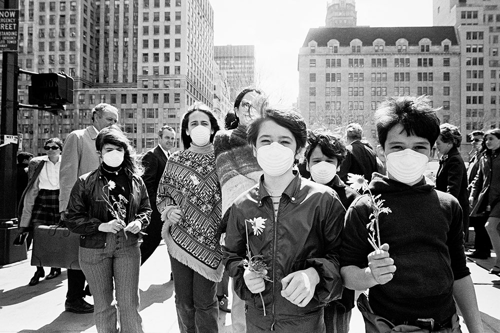 Youth march in the first Earth Day wearing dust masks carrying daisies