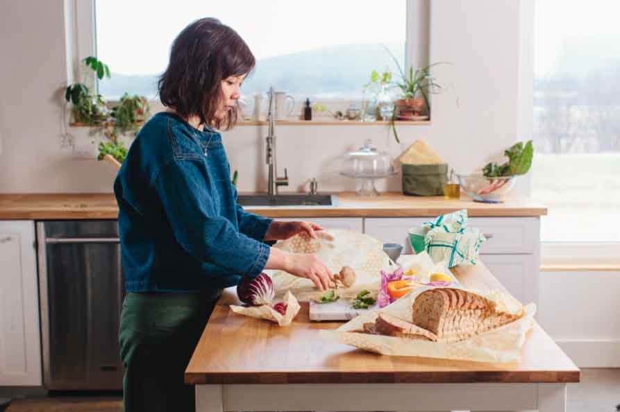 Woman preparing food on a kitchen island using bee''s wrap reusable food wraps