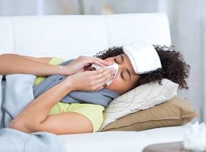 Sick woman on couch blowing nose