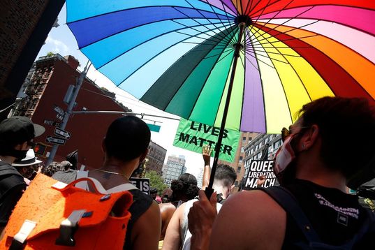 Pride Parade. Person standing with a multi-colored rainbow umbrella.