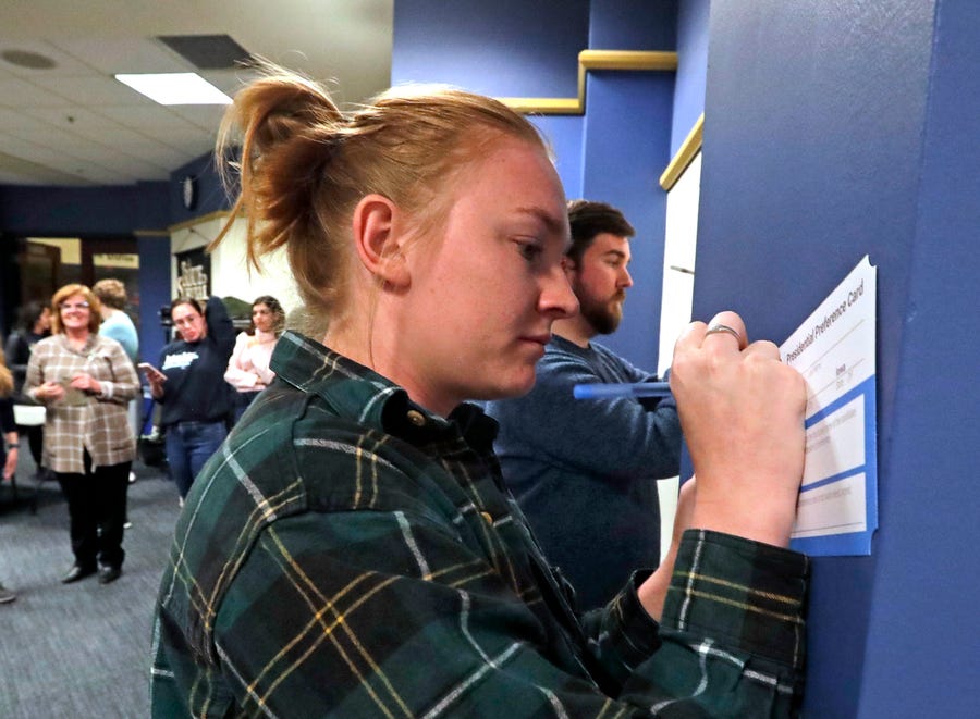 Cooper Warner, West Des Moines, signs her Presidential Preference Card to show her support for Elizabeth Warren at Marquette University on Monday night.  Seven Iowa residents gathered at the university to conduct a satellite caucus, one of 28 satellite caucuses as part of the Iowa caucuses.