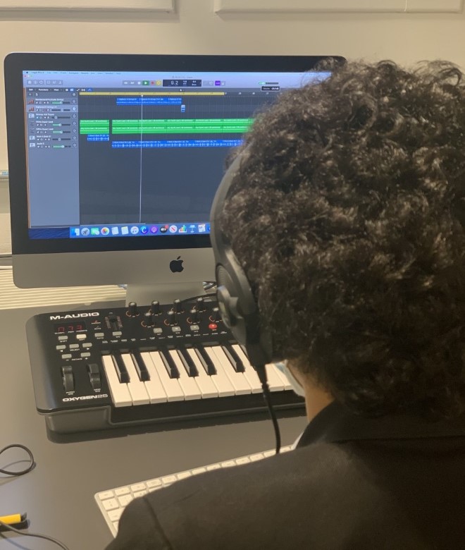 A school student uses a music keyboard and computer