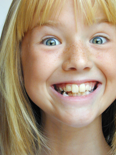 A freckle-faced young girl who looks happy and excited with a wide, toothy grin