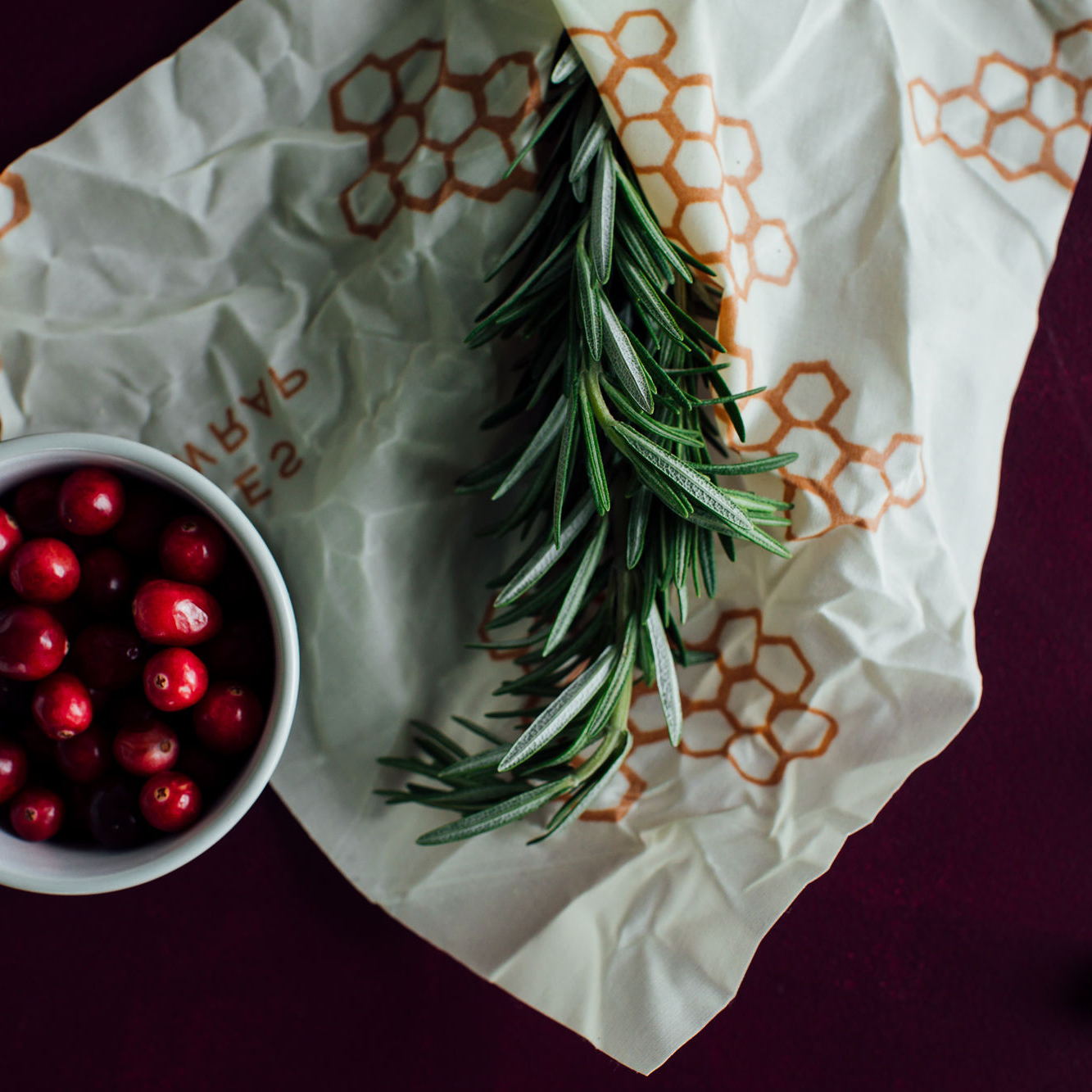 white christmas stocking on a wood table with fern leaves, cherries in a bowl, and package of bee''s wrap reusable food wrap