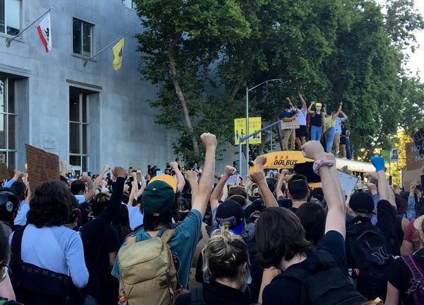 Protesters raise their fists in solidarity at the Hall of Justice while youth organizers lead chants from atop a school bus on June 3.