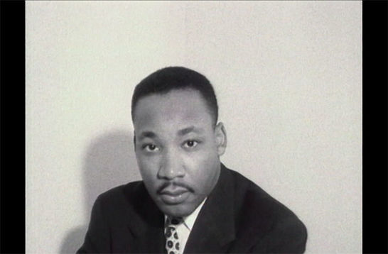 Martin Luther King, Jr. Black and photo of Black man with short dark hair, mustache, wearing a dark suit jacket, white, shirt and tie.