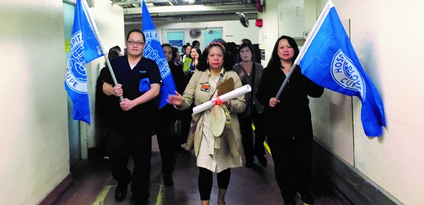 workers march indoors with blue hospital union flags