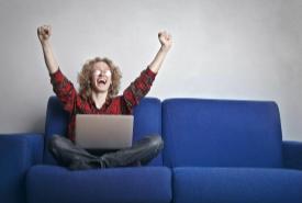 Woman sitting on a couch with raised arms. 