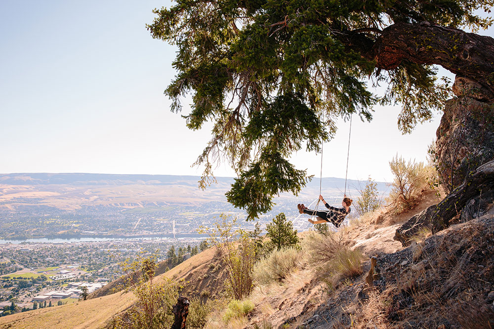 A young woman on a tree swing overlooking the city of Wenatchee