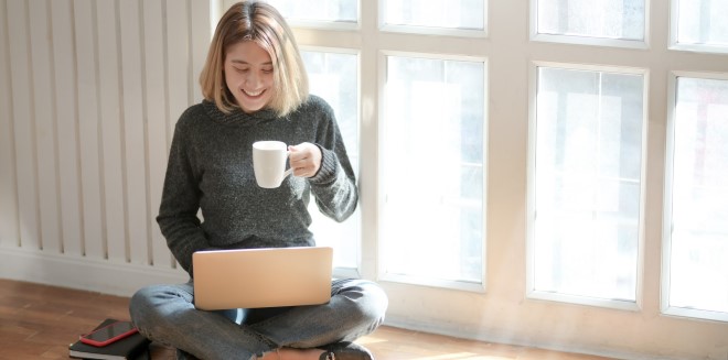 smiling woman on laptop drinking tea