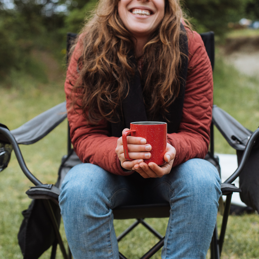 Person sitting in chair holding Speckled Red Camp Cup