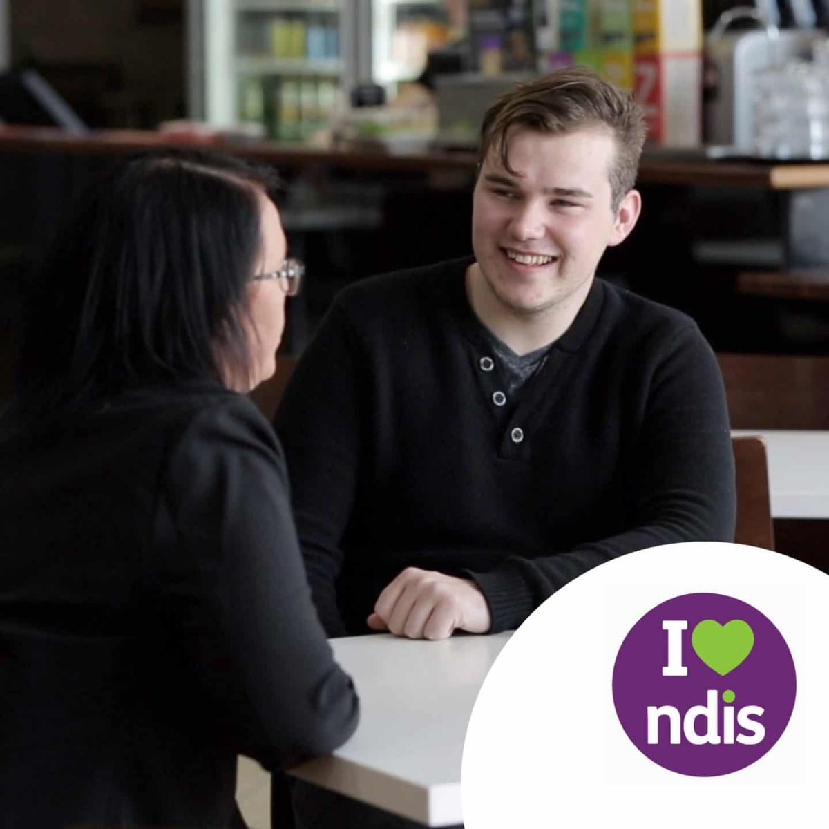 Vicki and Bradley talk at a local cafe, I heart NDIS logo