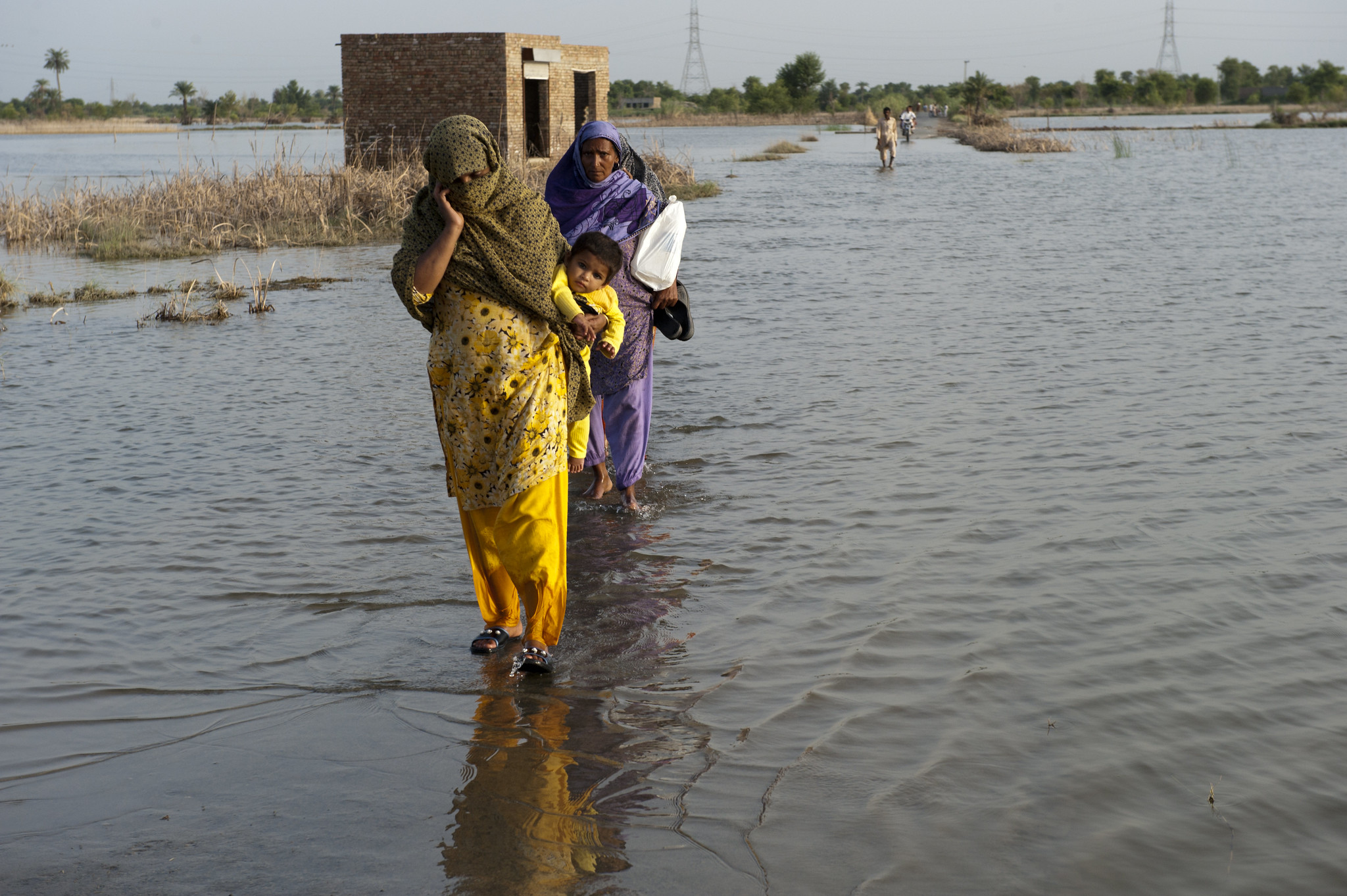 A family in Pakistan walks through flooded streets.